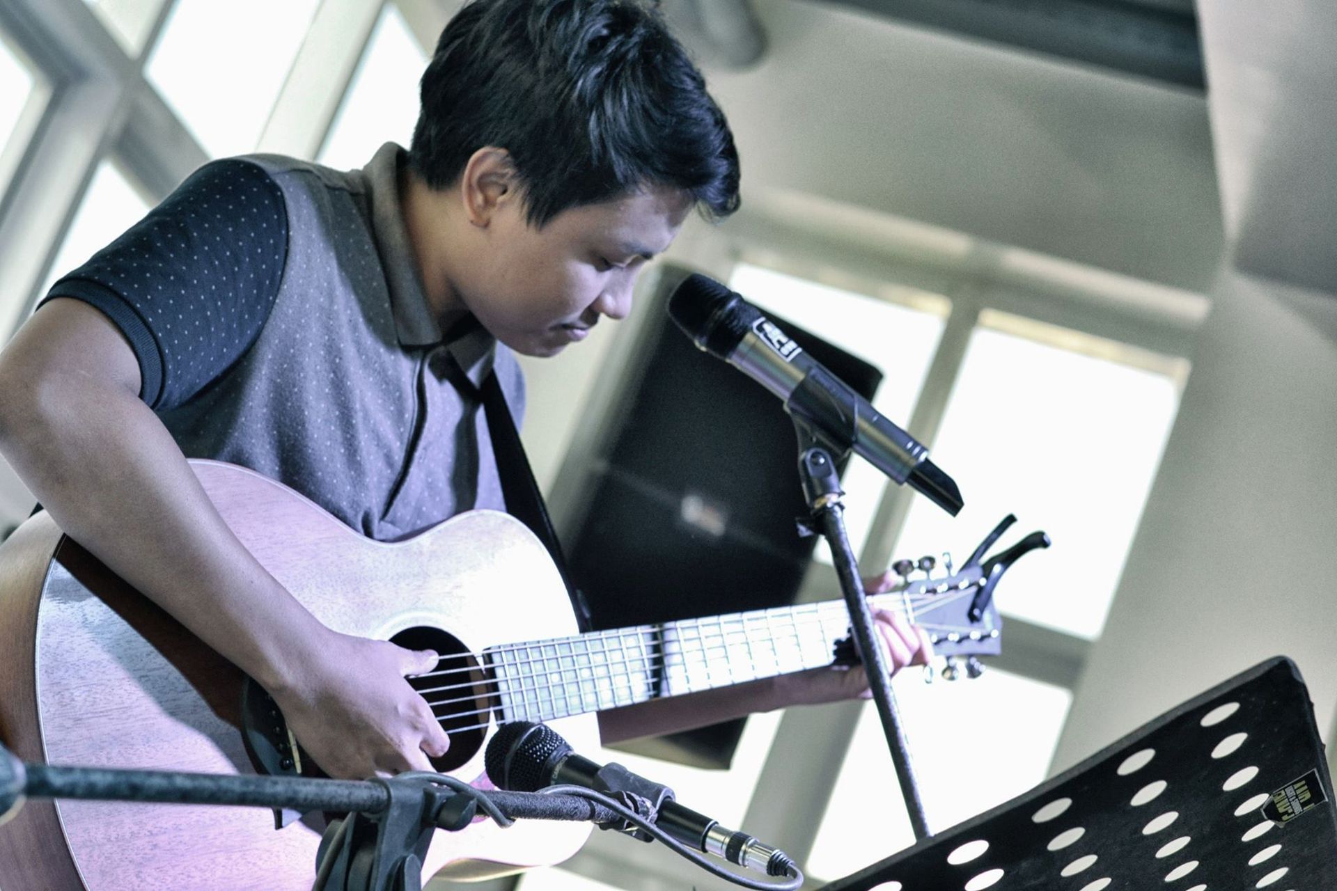 Jeroel holds a guitar in front of microphones